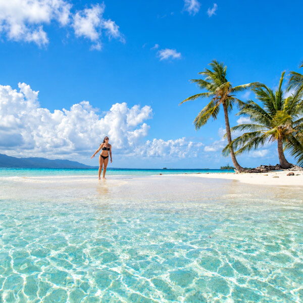 Traveler walking on a white sandbank next to palm trees